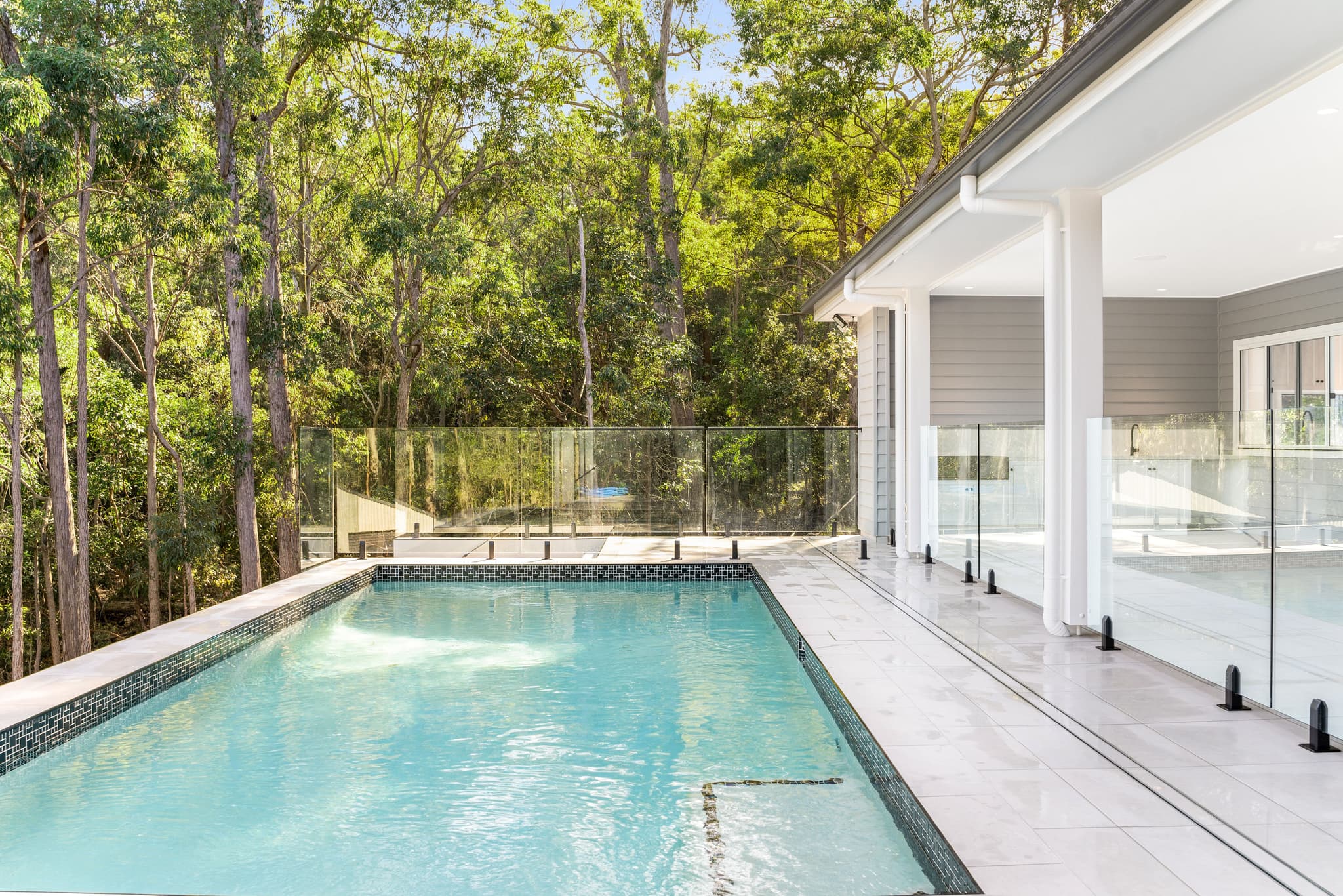 Custom Flascon home with a glass-fenced pool built directly alongside dense bushland in Brisbane