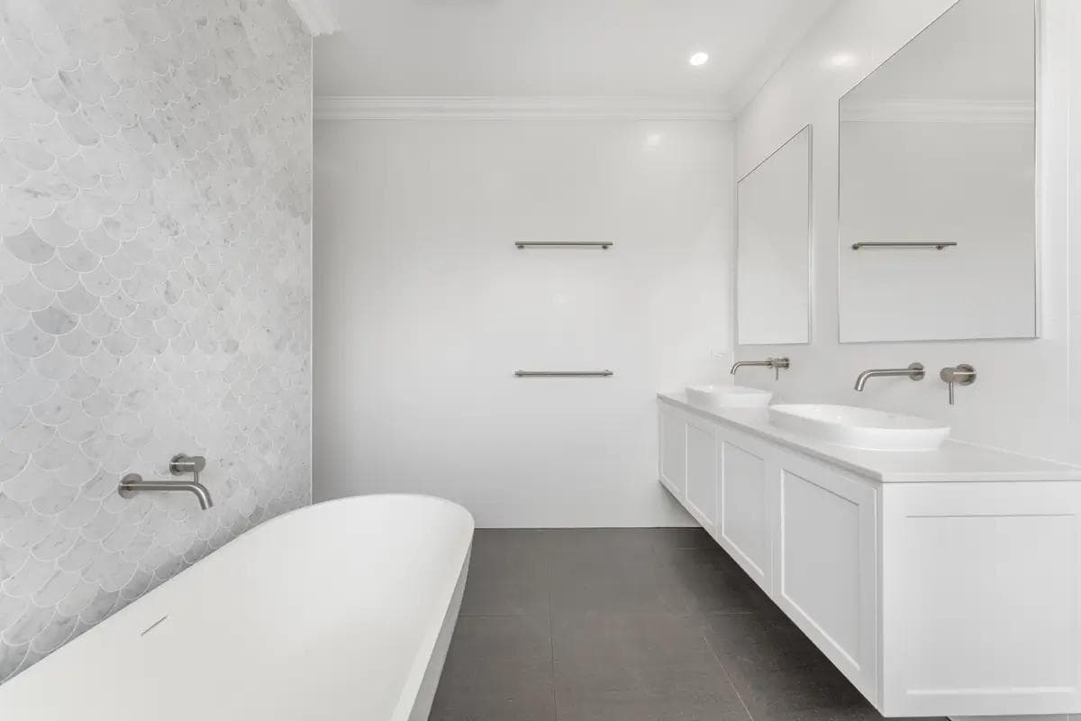 Bathroom with freestanding bath, fish-scale marble feature wall and floating double vanity.