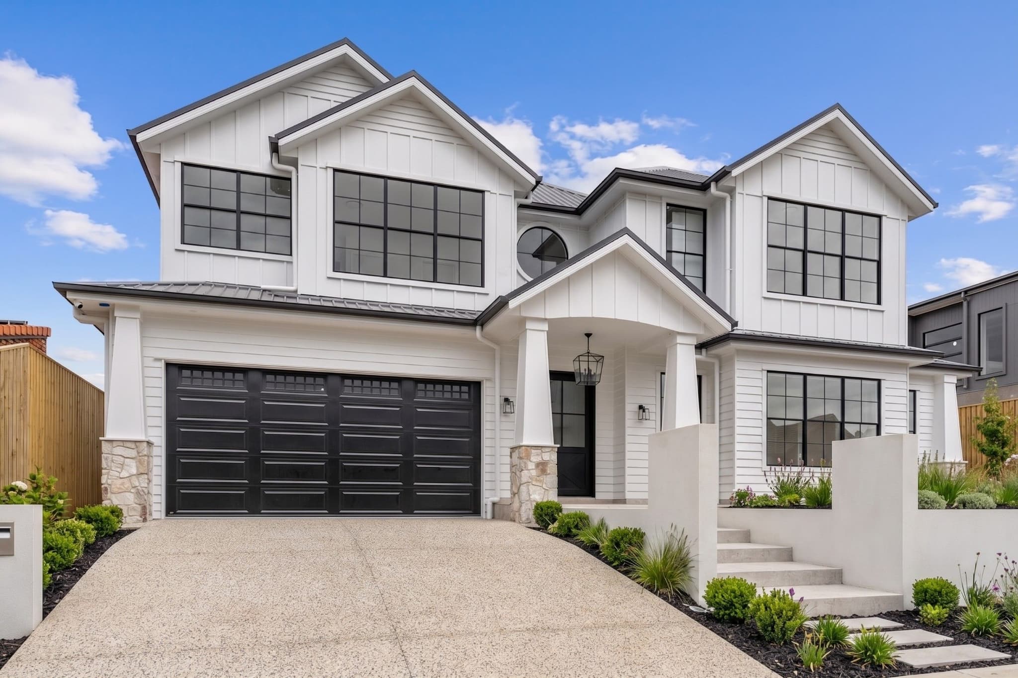 Modern farmhouse facade with board-and-batten cladding, black-framed windows and stone piers in Carindale.