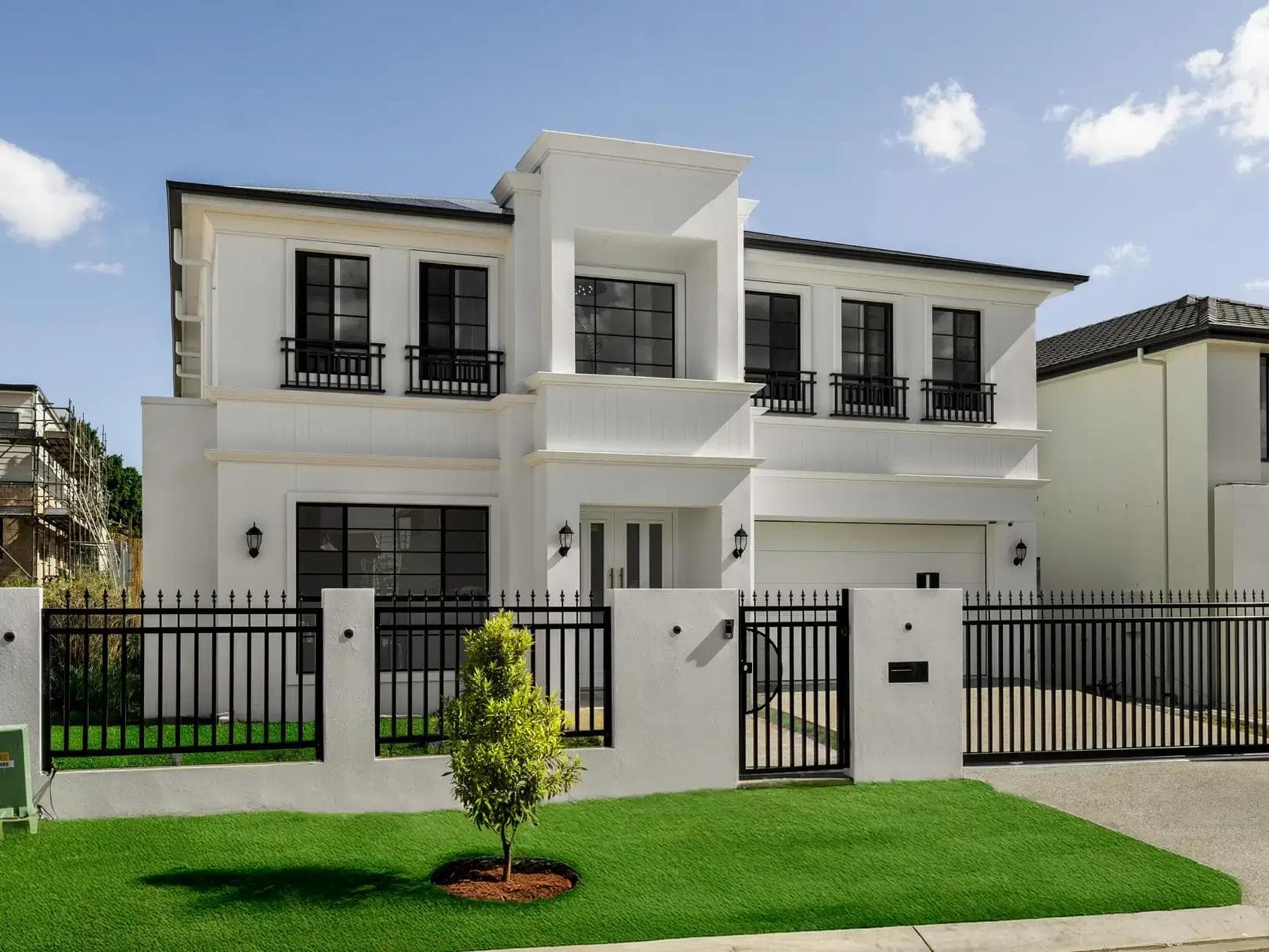 White rendered two-storey home with Juliet balconies and wrought iron fencing in Rochedale.