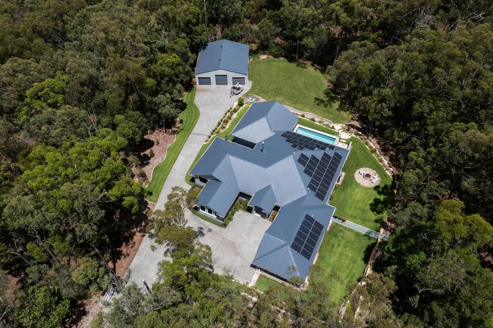 Aerial view of a custom Flascon acreage home with a separate shed and pool on a bushland block near Brisbane