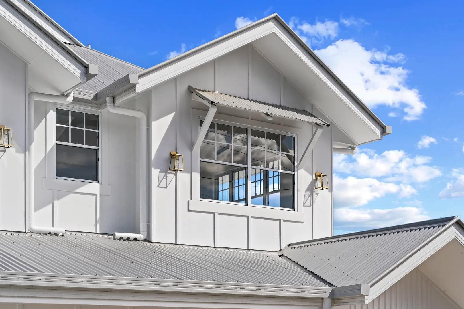 White board and batten gable with corrugated window awning and brass lanterns at Bundah House, Camp Hill.