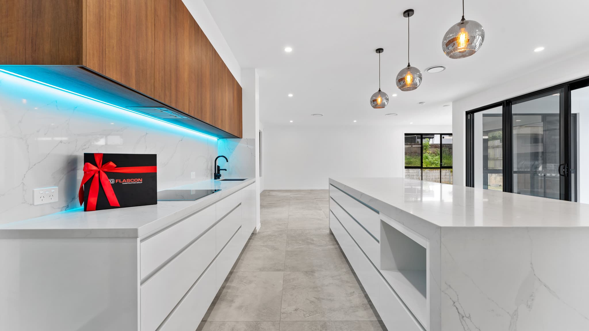 A ribboned Flascon handover gift box sitting on the kitchen bench of a newly completed Brisbane home