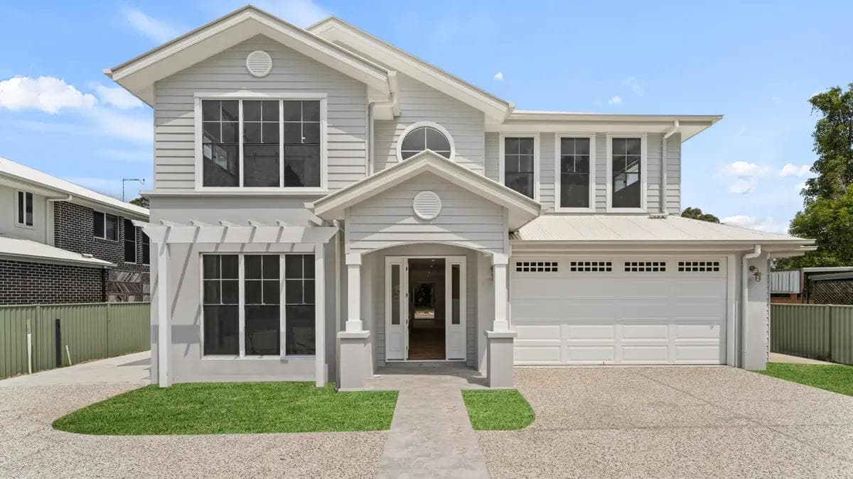 Hamptons-style two-storey home with grey weatherboard cladding and gabled portico in Belmont.