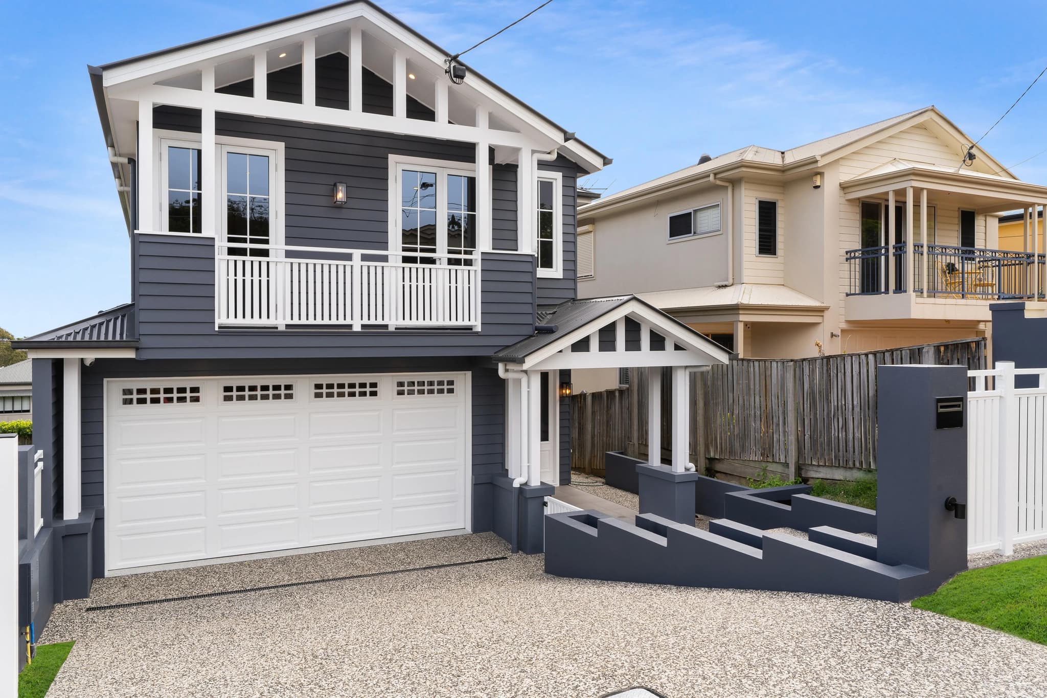 Two-storey Hamptons-style home in Greenslopes with navy weatherboard cladding and white trim.