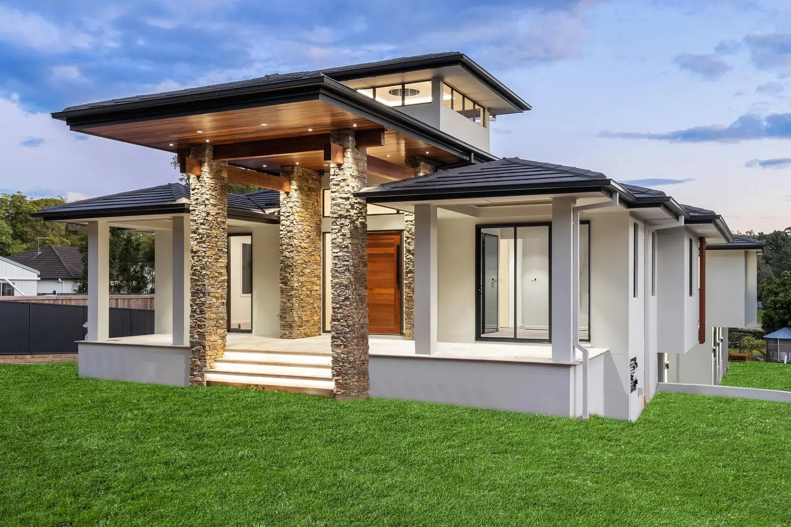 Resort-style home in Daisy Hill with stacked stone columns, timber-lined eaves and dark tiled roof.