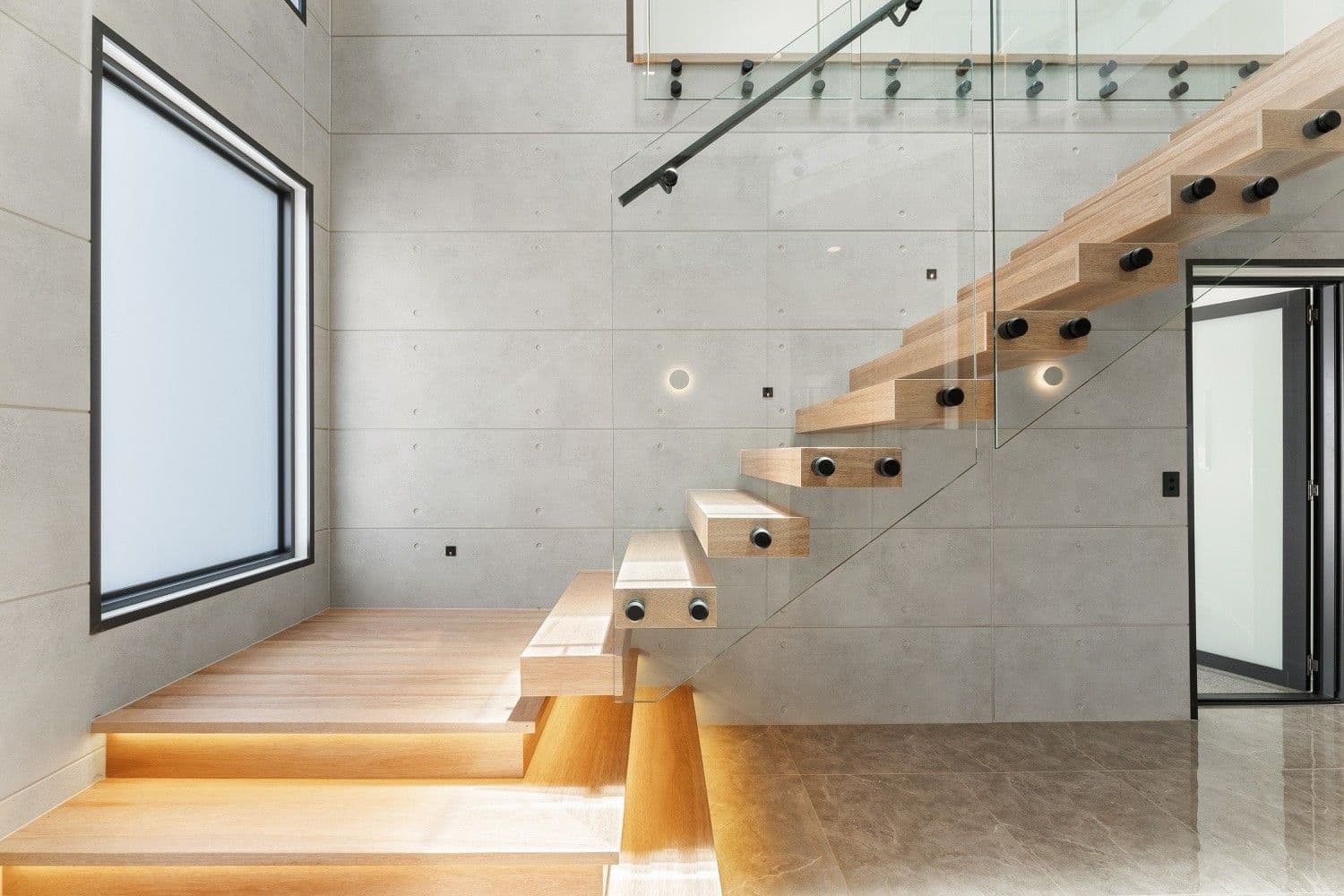 Floating timber staircase with glass balustrade against an off-form concrete feature wall.