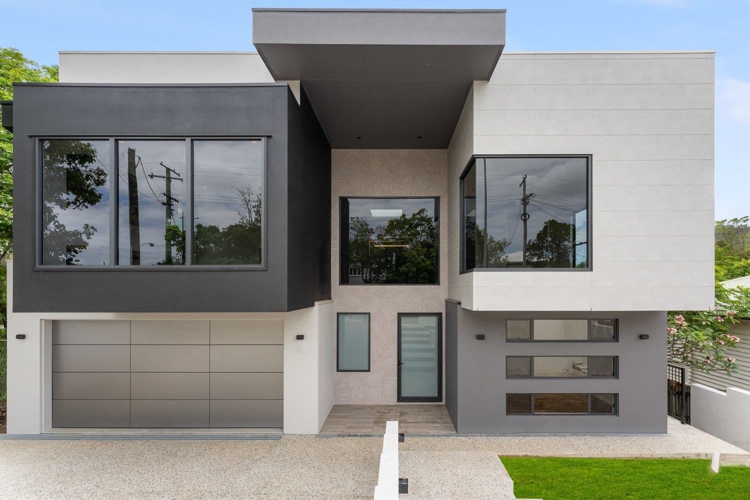 Bold contemporary facade in Indooroopilly with charcoal and off-form concrete forms above a grey garage.