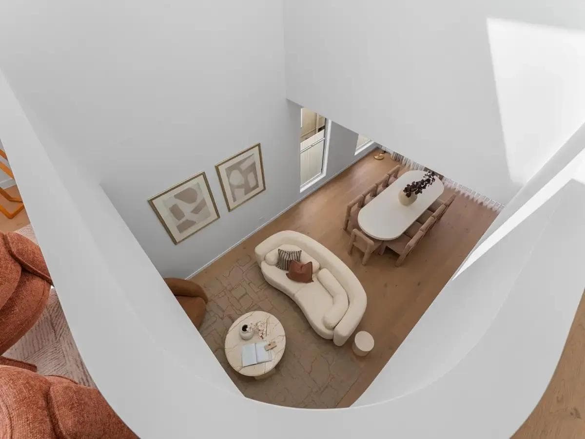 Looking down through the curved void into the furnished living and dining area of Pinedale House, Morningside, a luxury custom home by Flascon Construction Group