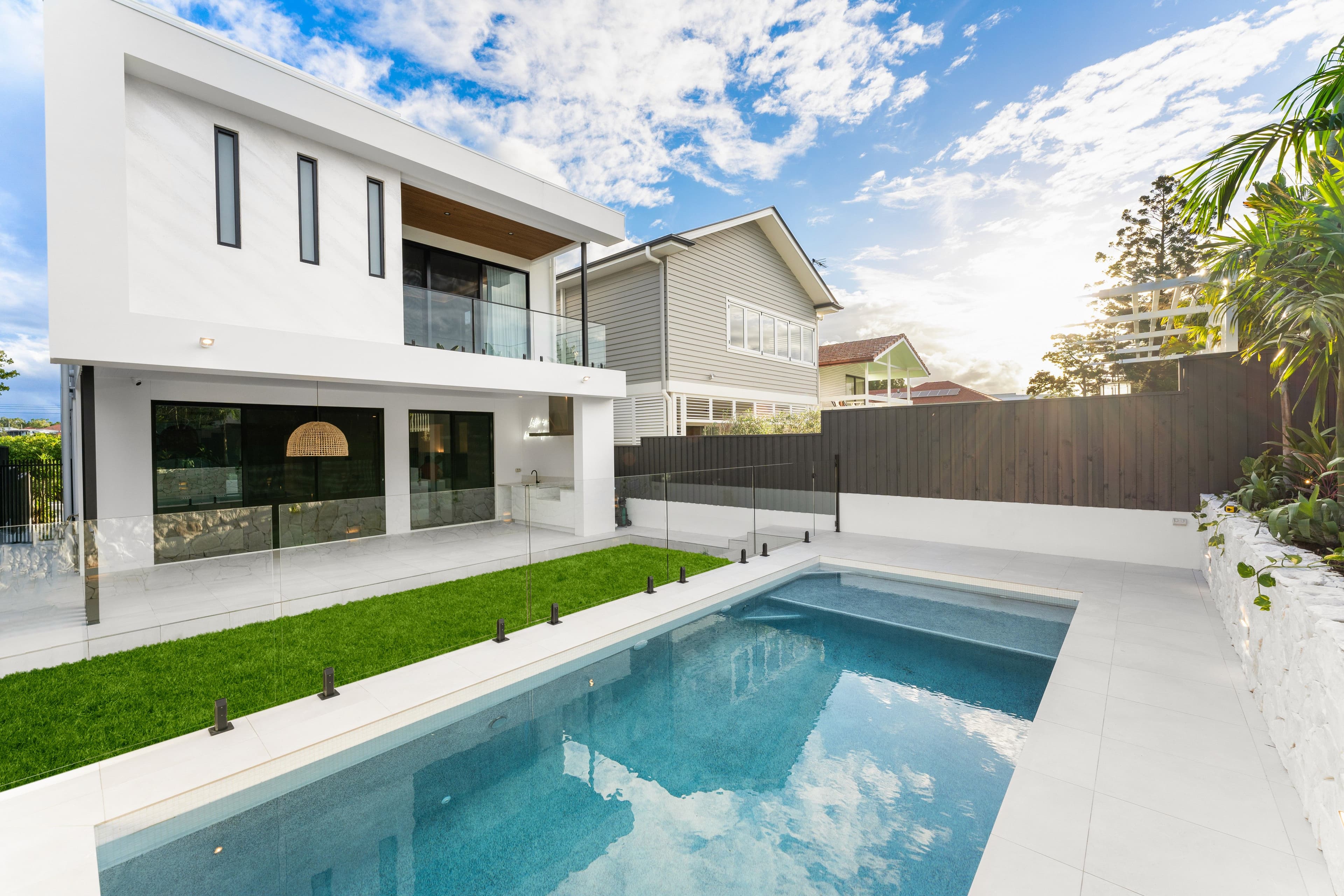 A custom modern two storey house in Brisbane featuring a flat roof, large alfresco, and integrated swimming pool.