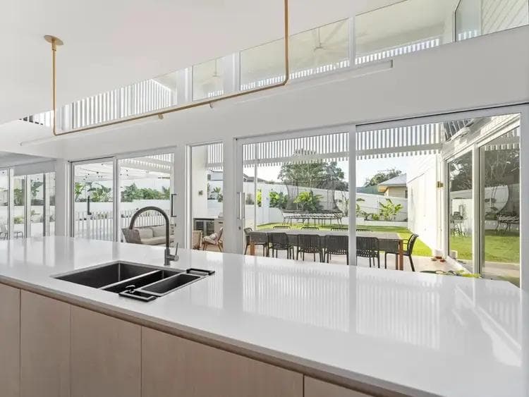 Finished kitchen at Porteous House, Seven Hills, a custom home by Flascon Construction Group, with the island bench, tapware and sliding doors opening to the alfresco